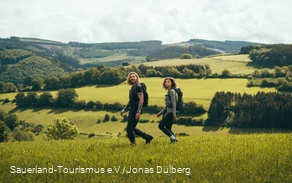Zwei junge Leute wandern oberhalb von Sundern-Hagen über eine Wiese